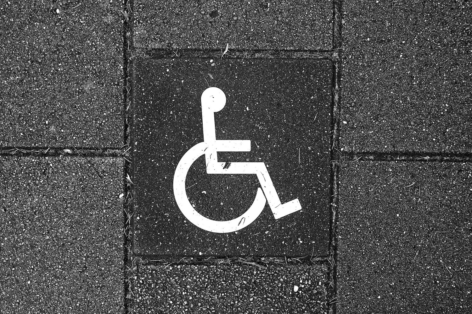 The pictograph of a person in a wheelchair on the pavement of a packing lot.